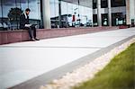 Businessman sitting in passage of office building and using laptop