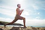 Man performing stretching exercise on beach