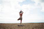 Man performing yoga on beach