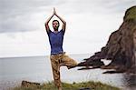 Man performing yoga on cliff