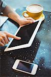 Close-up of woman using digital tablet while having coffee in café