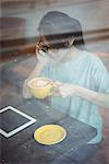 Young woman talking on mobile phone while having coffee in café