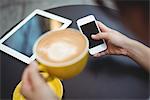 Woman using mobile phone while having coffee in café