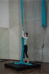 Gymnast holding blue fabric rope on landing mat in fitness studio