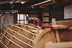 Man preparing wooden boat frame in boatyard