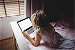 Woman using laptop in bedroom at home