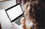 Woman using laptop in bedroom at home