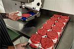 Mid section of butcher preparing a raw hamburger patties in the butchers shop