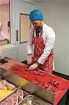 Butcher chopping red meat at butchers shop