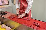 Mid section of butcher chopping red meat at butchers shop