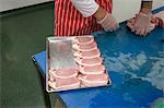 Mid section of butcher arranging steaks in tray at butchers shop