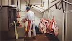 Butcher working in meat storage room at butchers shop