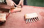 Hands of butcher cutting pigs ribs at butchers shop