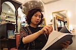 Stylish woman reading a magazine while sitting under a hairdryer at hair salon