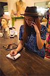 Female staff taking order on mobile phone in boutique store