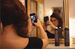 Woman taking selfie from mobile phone at saloon