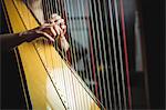 Mid-section of woman playing a harp in music school
