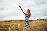 Rear view woman standing with arms outstretched in field