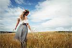 Beautiful woman touching wheat in field