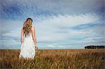 Rear view of woman standing in wheat field on a sunny day