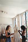 Female fashion designers working on digital tablet in the studio