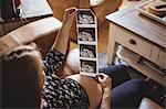Pregnant woman looking at a sonography in living room at home