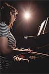 Female student playing piano in a studio