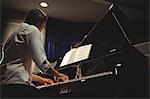 Female student playing piano in a studio