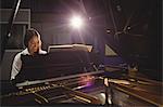 Female student playing piano in a studio