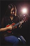 Beautiful woman playing a guitar in music school