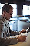 Businessman using mobile phone while having coffee at café