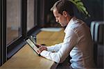 Businessman working on a digital tablet at cafe