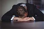 Exhausted businessman sitting with his head down on office desk