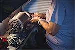 Mid-section of craftswoman working on a machine in workshop