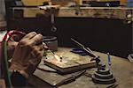 Hands of craftswoman using blow torch in workshop