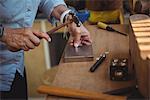 Mid-section of craftswoman using hammer in workshop