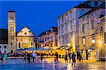 People sightseeing in St Stephen's Square with restaurant and Cahtedral of St Stephen in background in Old Town of Hvar on Hvar Island, Croatia