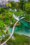 Footbridge crossing the turquoise lake water and waterfalls at the Plitvice Lakes National Park, Croatia