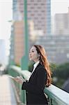 Young Japanese businesswoman with tablet by a river downtown Tokyo