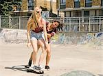 Two women practising skateboarding balance in skatepark