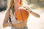Mid section of young woman practising on basketball court