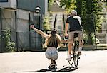 Rear view of female skateboarder and male cyclist  on basketball court