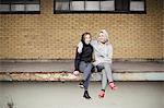 Portrait of two female runner friends sitting on warehouse platform