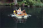 Three adult female friends hand paddling rowing boat on lake, Sattelbergalm, Tirol, Austria