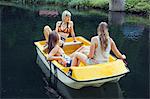 Three adult female friends in rowing boat on lake, Sattelbergalm, Tirol, Austria
