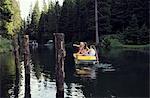 Three adult female friends pointing from rowing boat on lake, Sattelbergalm, Tirol, Austria