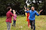 Family fooling around outdoors, teenage boy blowing bubbles at family