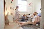 Mid adult woman sitting on living room floor with laptop whilst son and daughter play