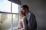 Mid adult couple gazing out through bedroom window