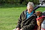 Man and dog sitting in car boot